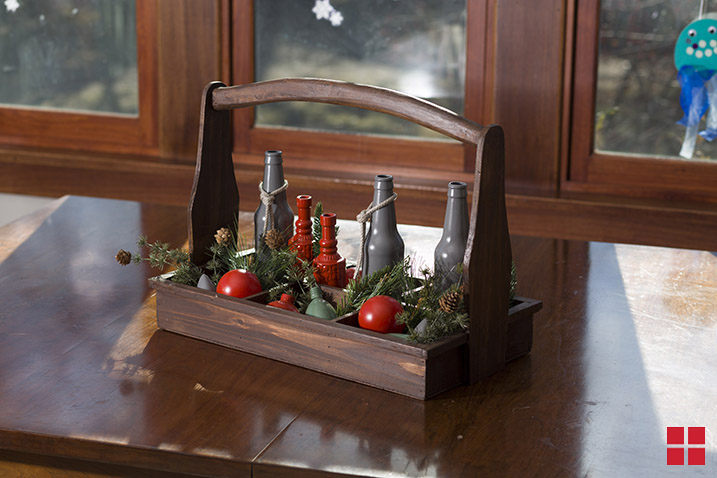 Wood basket filled with vases, ornaments and evergreen branches.